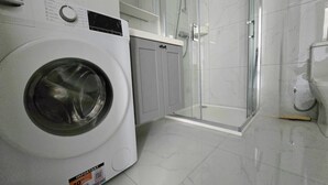 A laundry room with a front-loading washing machine, a glass-enclosed shower, and a toilet. - 3 bedroom, 2 bathroom Brand new Apartment in Central Gozo (Ir-Rabat Għawdex)