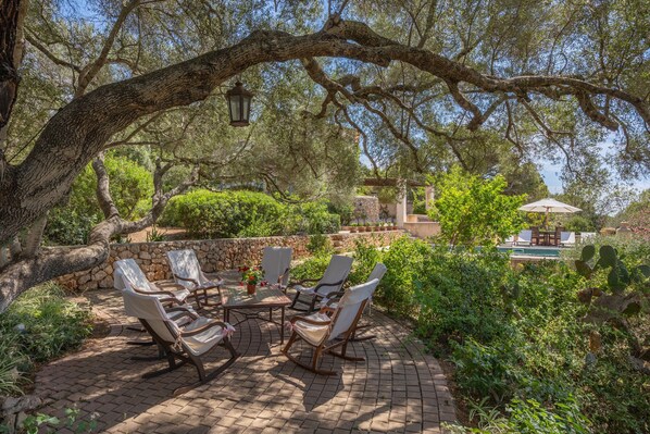 A patio with four chairs, a table, and a hanging lantern. - Holiday Home 'Ca Na Tonina' with Sea Views and Private Pool (S'Alqueria Blanca)
