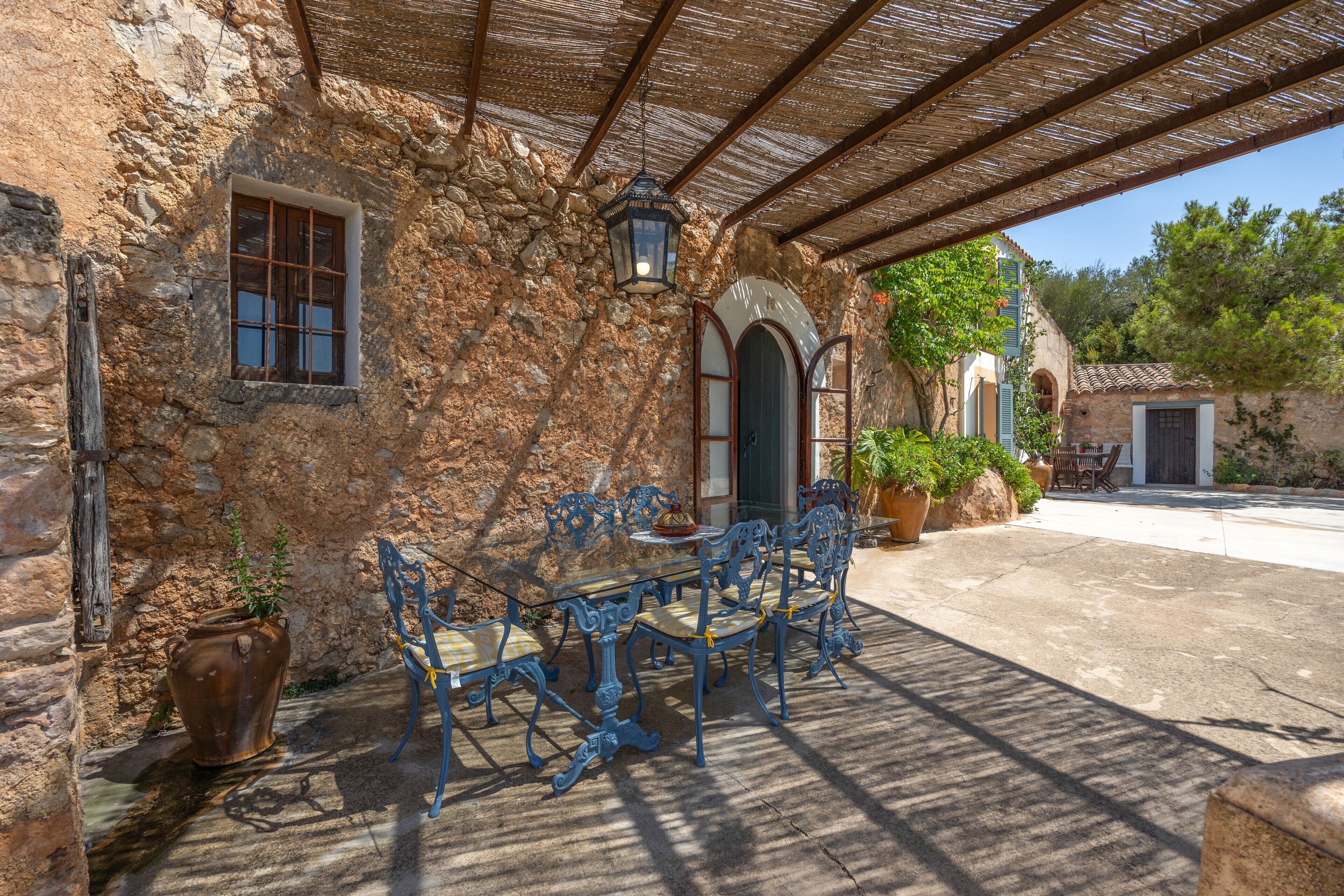 A stone building with a covered patio, outdoor seating, and a lantern.