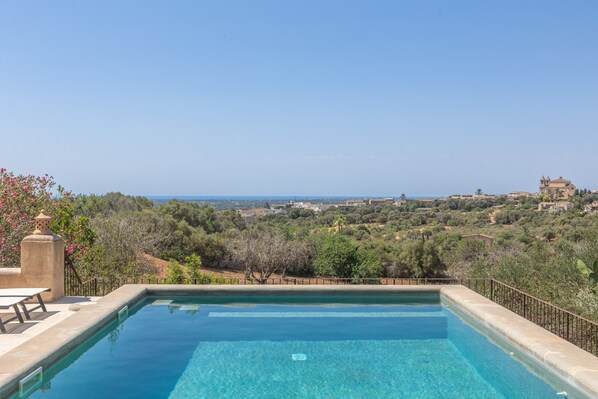 A clear swimming pool with a view of a hilly landscape and distant buildings.