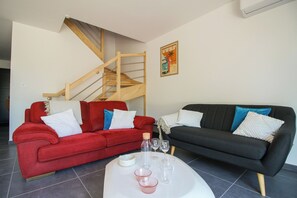 Een woonkamer met twee banken, een salontafel en een houten trap.