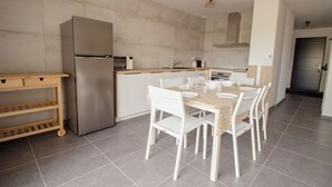 Una cocina moderna con un refrigerador de acero inoxidable, armarios blancos, una encimera de madera y una mesa de comedor para cuatro.