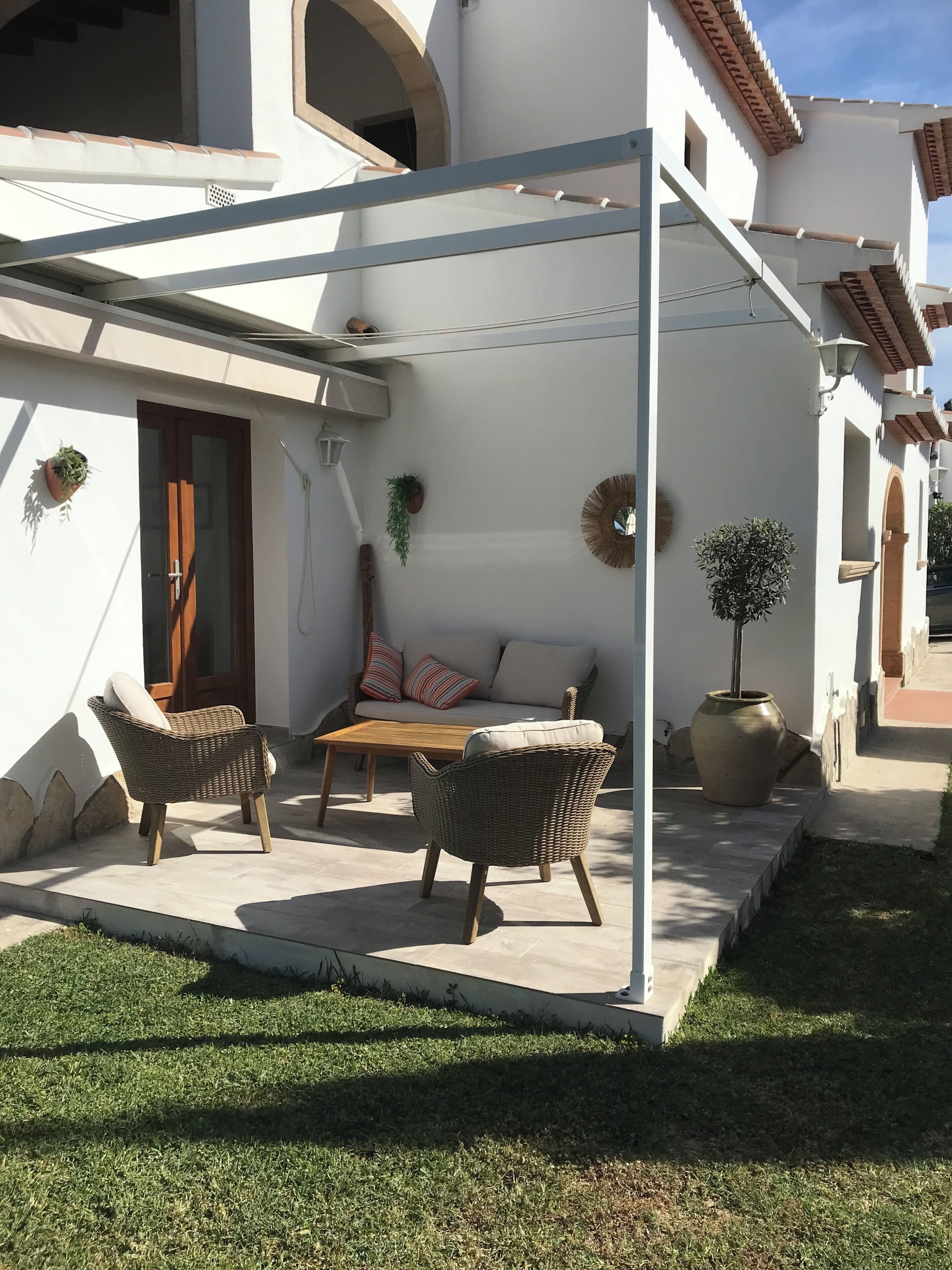 Un espace patio aménagé avec des meubles en osier, un canapé et une plante en pot.