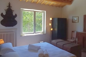 Una stanza con un letto, una finestra, un elemento decorativo a parete, una lampada e una sedia.