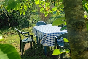Un'area salotto esterna con tavolo e sedie in un giardino, con tovaglia a quadri.