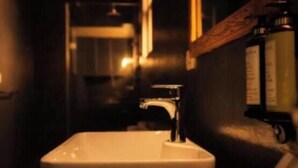 Un baño con lavamanos, espejo y artículos de aseo.