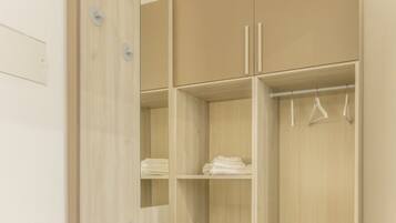 Een houten garderobe met twee deuren, een kledingstang en een spiegel.