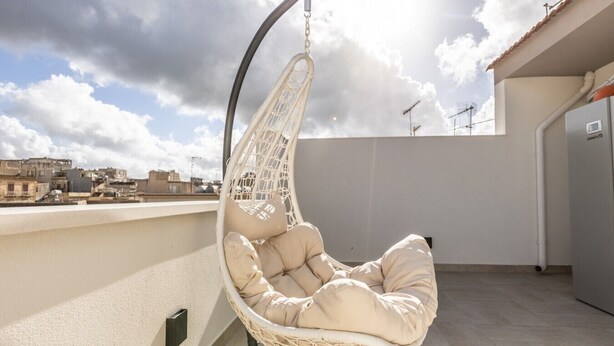 A hanging chair on a rooftop terrace with a cityscape view. - Nova Suite - Apartment 200 (Calatafimi)