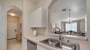 A kitchen with a double sink, white cabinets, and a dishwasher. - WP301 - 3BR Condo Near Walt Disney World (Kissimmee)