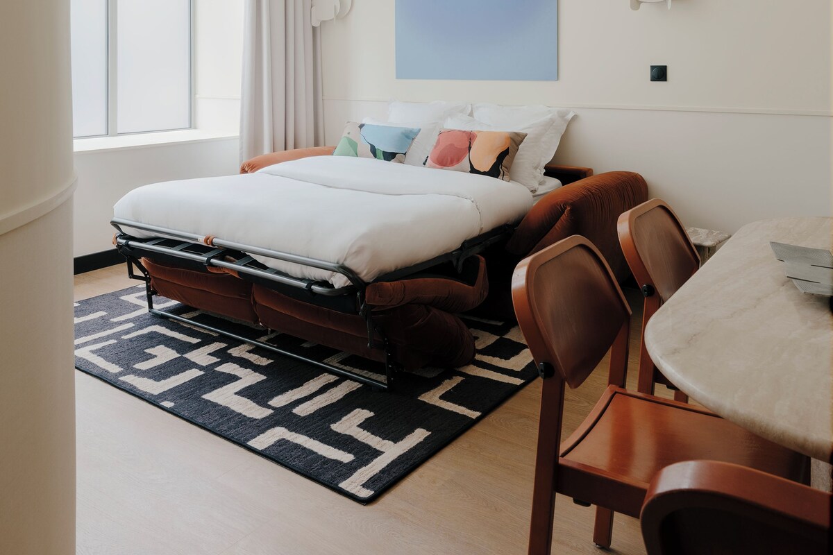 A modern bedroom with a bed, a desk, and a chair.