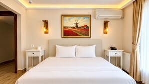 Hotelkamer met een groot bed, twee nachtkastjes, een schilderij van een windmolen en een airconditioning.