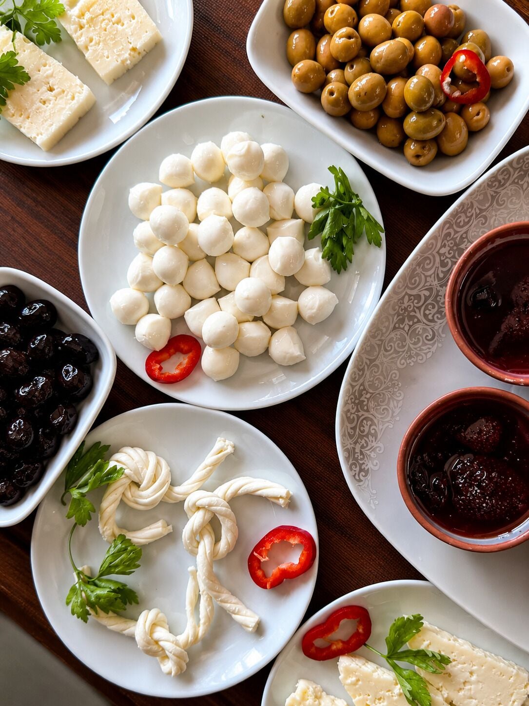Diversos productos alimenticios, como bolitas de mozzarella, aceitunas y un plato con salsa roja.