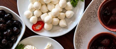 Diversos productos alimenticios, como bolitas de mozzarella, aceitunas y un plato con salsa roja.