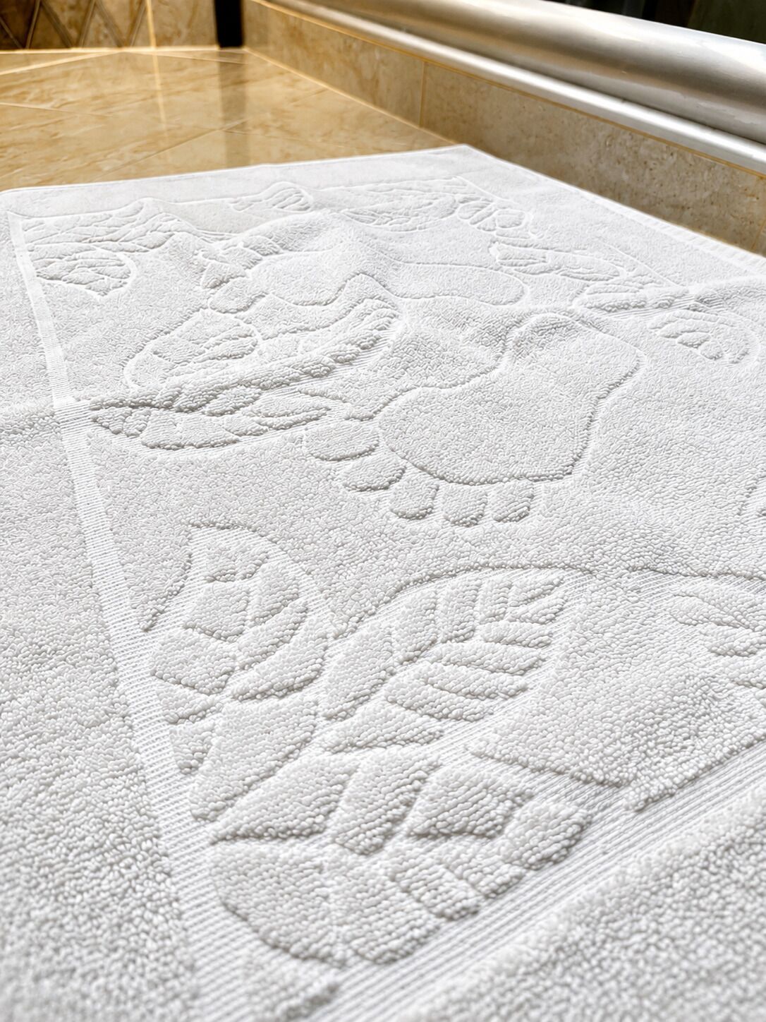 A bathroom with a white textured towel and a marble countertop.
