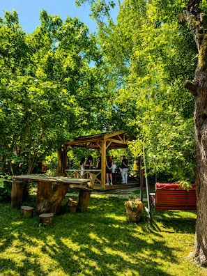 Un belvédère en bois, situé dans un parc verdoyant, avec des personnes qui s’y trouvent.