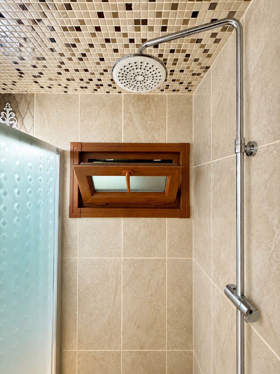 Une douche équipée d’un pommeau de douche à main, d’une paroi en verre et d’un mur carrelé.