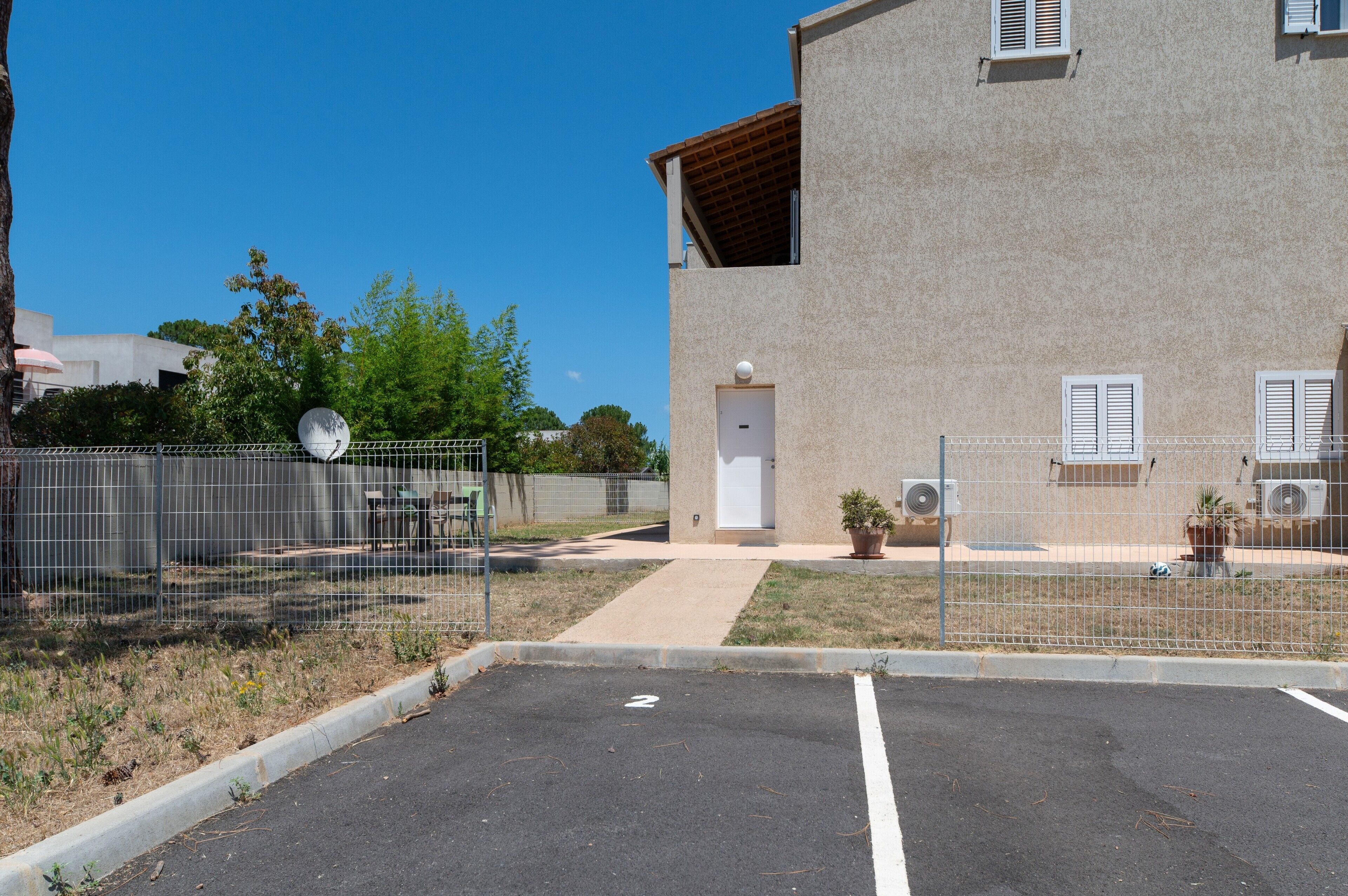 A building with a gated parking area, a door, and satellite dishes.