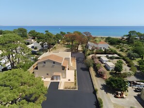 Vista aérea de un área residencial con una casa destacada que cuenta con un patio central, rodeado de abundante vegetación y una vista despejada del mar.
