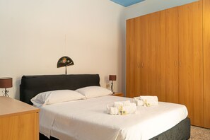 Ein Hotelzimmer mit Bett, Nachttisch, Lampe und Kleiderschrank.