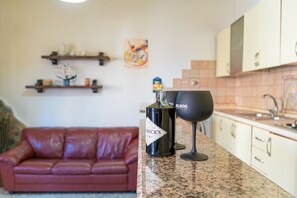 Eine Küche mit einer Granitabdeckung, einem roten Ledersofa und einem kleinen dekorativen Gegenstand an der Wand.