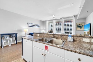 Eine moderne Küche mit einer Granit-Arbeitsplatte, einer Edelstahl-Spüle und weißen Schränken.