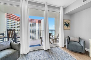 Ein Balkon mit Blick auf hohe Gebäude, eine Sitzecke mit Stühlen und einem Teppich.