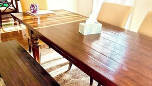 Une table à manger en bois, avec des bancs, une boîte à mouchoirs et un objet décoratif posé sur la table.