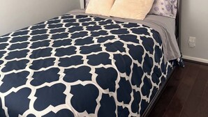 Une chambre à coucher avec une tête de lit en bois foncé, une couvre-lit à motifs bleu marine et blanc, et deux oreillers.