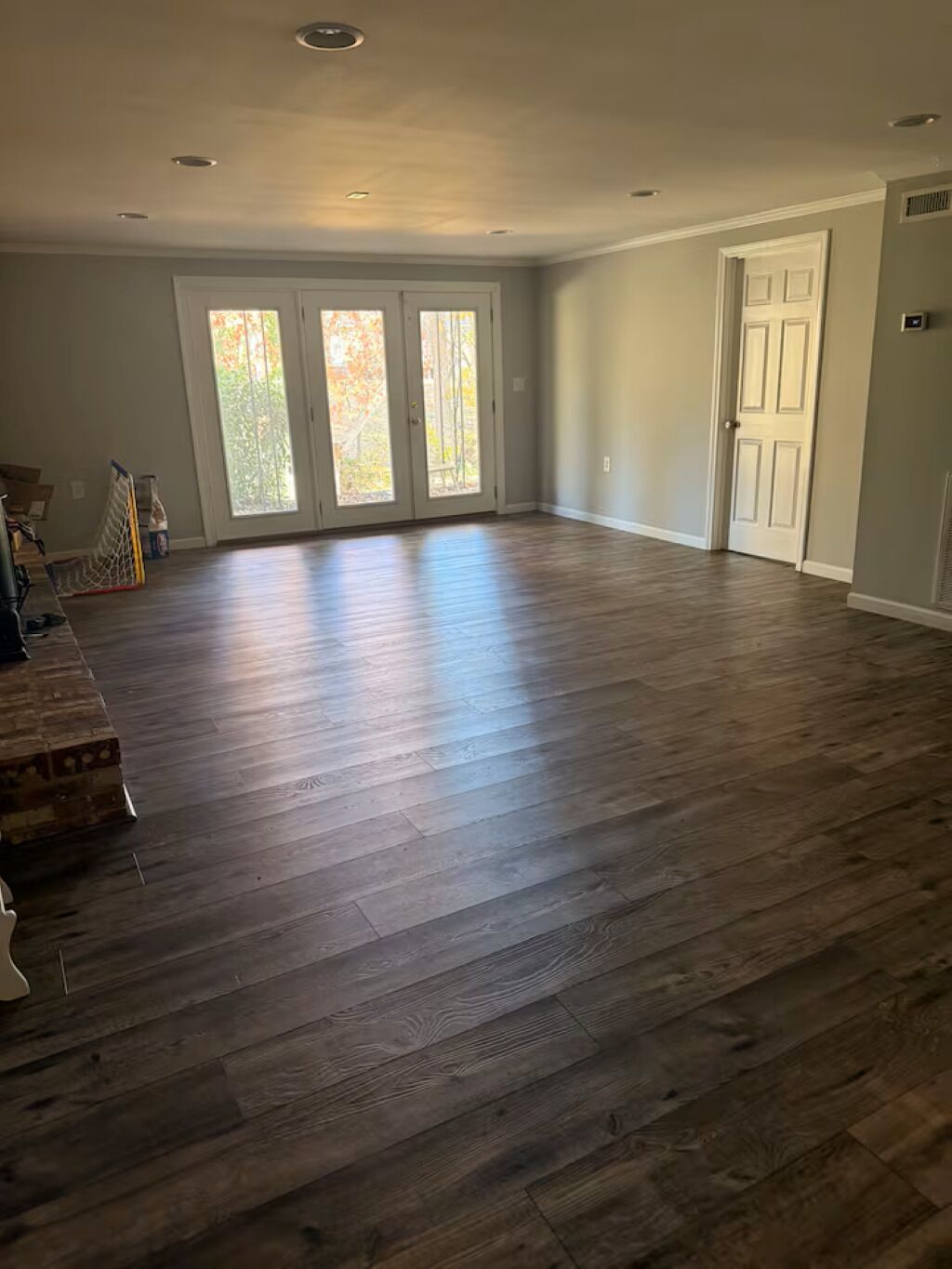 A spacious room with hardwood flooring, a large sliding glass door, and a white door.