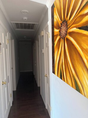 A hallway with white doors and a large floral painting on the wall. - Upscale Family Retreat • Creek Views (Shelby)