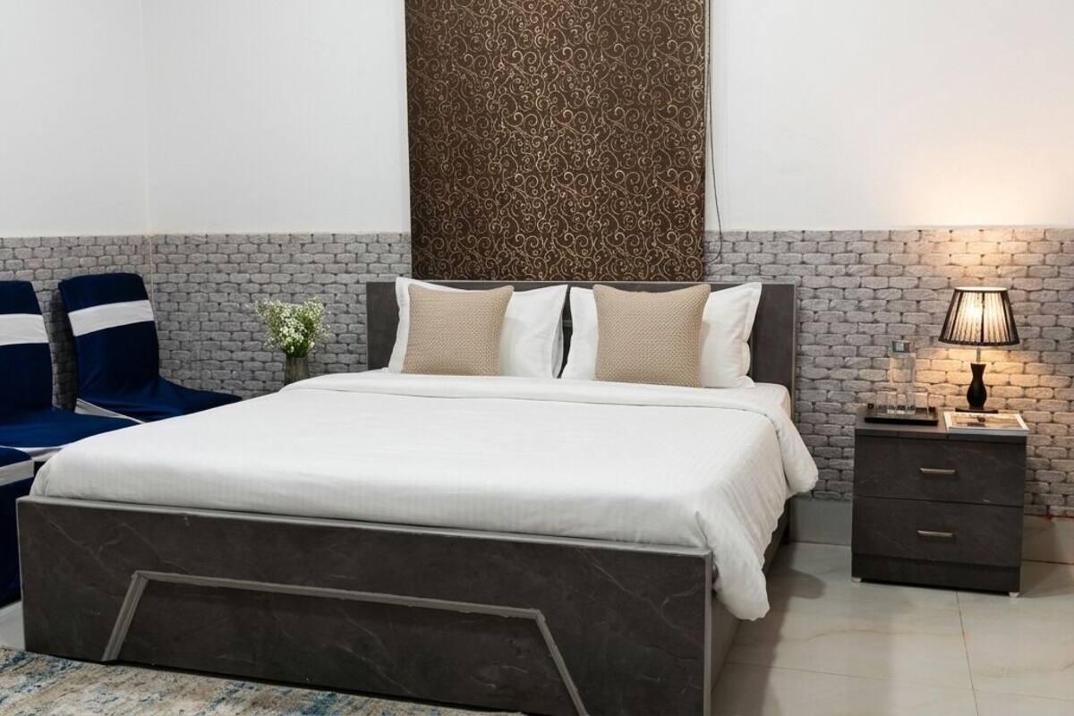 Un dormitorio con una cama, dos sillas azules, una mesita de noche y una lámpara.