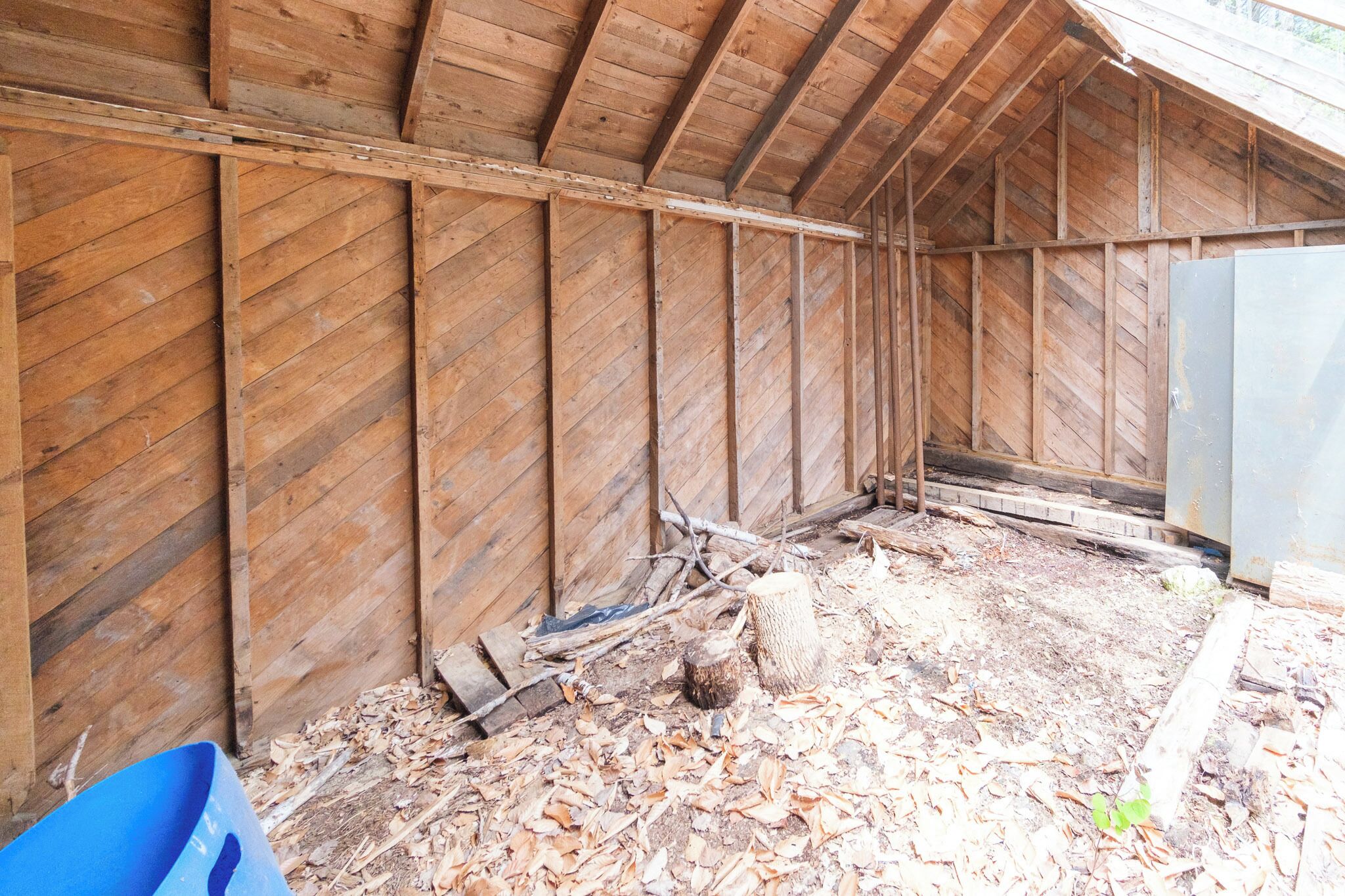A wooden structure with a sloped roof and a dirt floor.