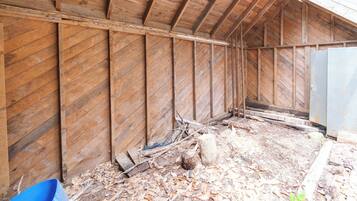 A wooden structure with a sloped roof and a dirt floor.