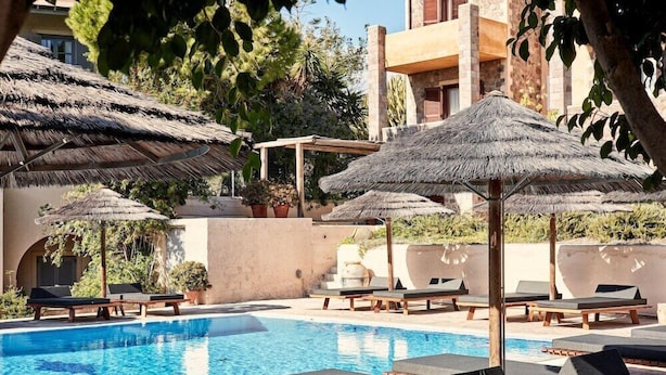 A pool area with lounge chairs and thatched umbrellas. - Angelina Aegina Escape (Aegina)
