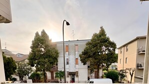 Un balcón con muebles de madera, vista a la calle y edificios al fondo.