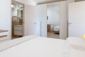 Een slaapkamer met een bed, een kledingkast en een badkamer die door een open deur zichtbaar is.