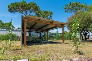 Un espacio al aire libre techado con un banco, una mesa y sillas.