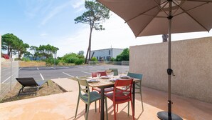 Un patio al aire libre con una mesa, sillas y una sombrilla.