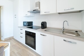 A modern kitchen with white cabinets, a built-in oven, a microwave, a coffee maker, and a stainless steel sink. - Apartment 'La Dolce Vita 3' with Sea View, Wi-Fi and Air Conditioning (Borgo)