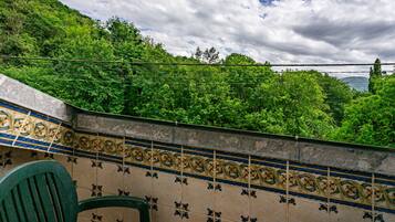 A tiled wall with a decorative pattern, a green chair, and a view of a lush green hillside.