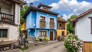 A two-story building with a balcony, a small outdoor seating area, and a wooden fence. - Casa Luis with Mountain Views (Llenín)