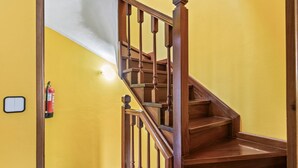 A wooden staircase with a handrail, a fire extinguisher on the wall, and a light switch. - Casa Luis with Mountain Views (Llenín)