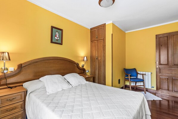 Un dormitorio con una cama de madera, una mesita de noche, una silla y un armario.