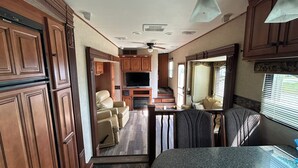 A compact RV interior with a kitchenette, a seating area, and a television. - What a View Cheticamp (Chéticamp)