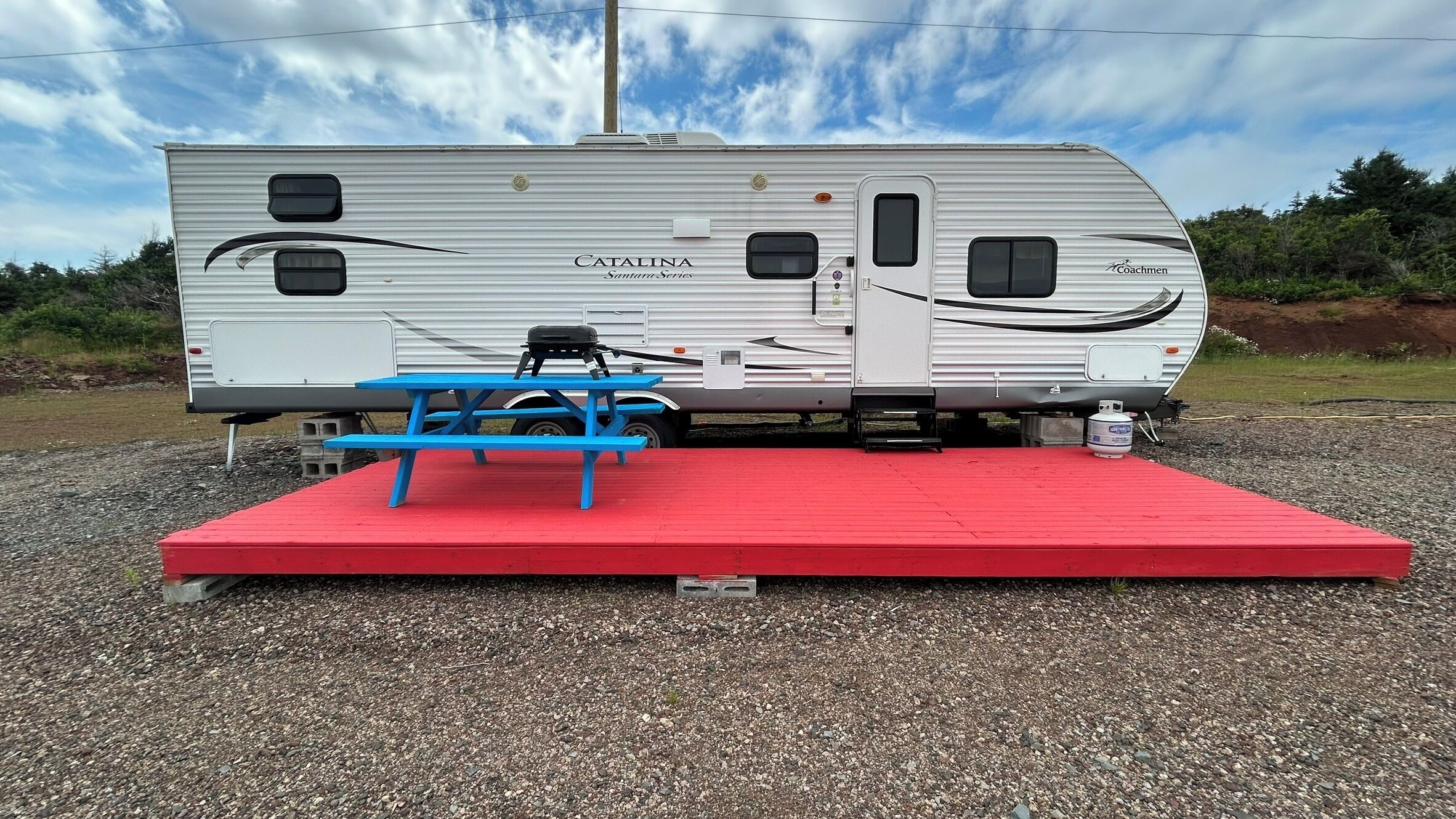 A Catalina Santana Series RV with a picnic table and red platform.