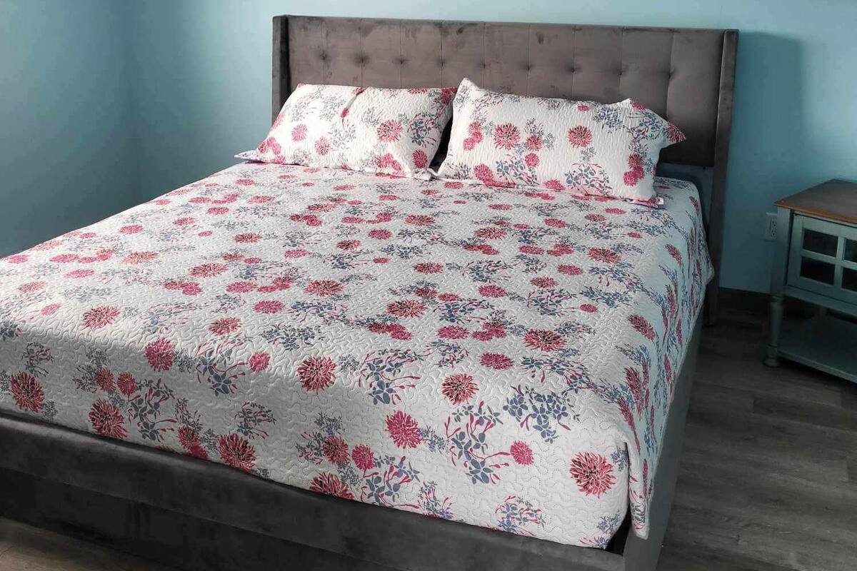 Un dormitorio con una cama, una mesita de noche y una pared azul.