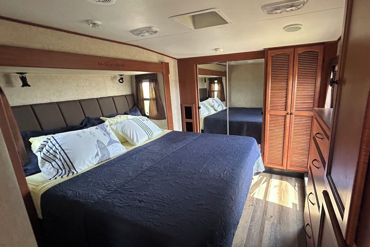 Un dormitorio con cama, armario y espejo.