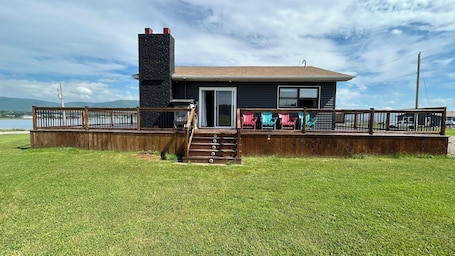 A house with a deck, a chimney, and a view of the water.