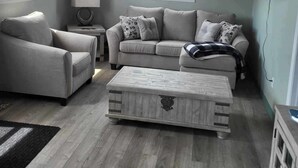 A living room with a sofa, armchair, and a coffee table. - What a View Cheticamp (Chéticamp)