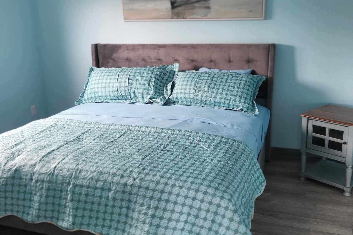 Un dormitorio con cama, mesita de noche y un cuadro en la pared.